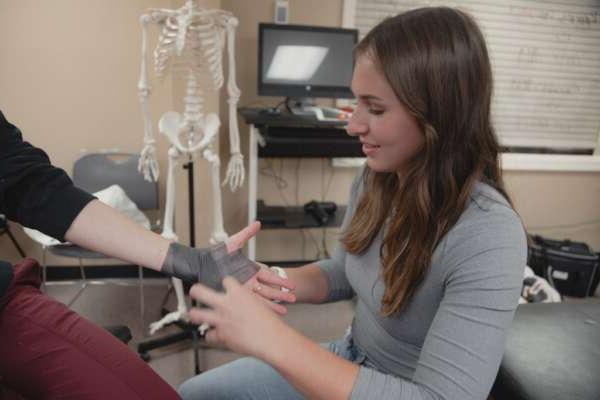 student learning to wrap an injured wrist